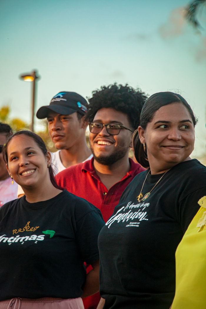 A diverse group of young adults smiling outdoors during a sunny day, fostering friendship and happiness.