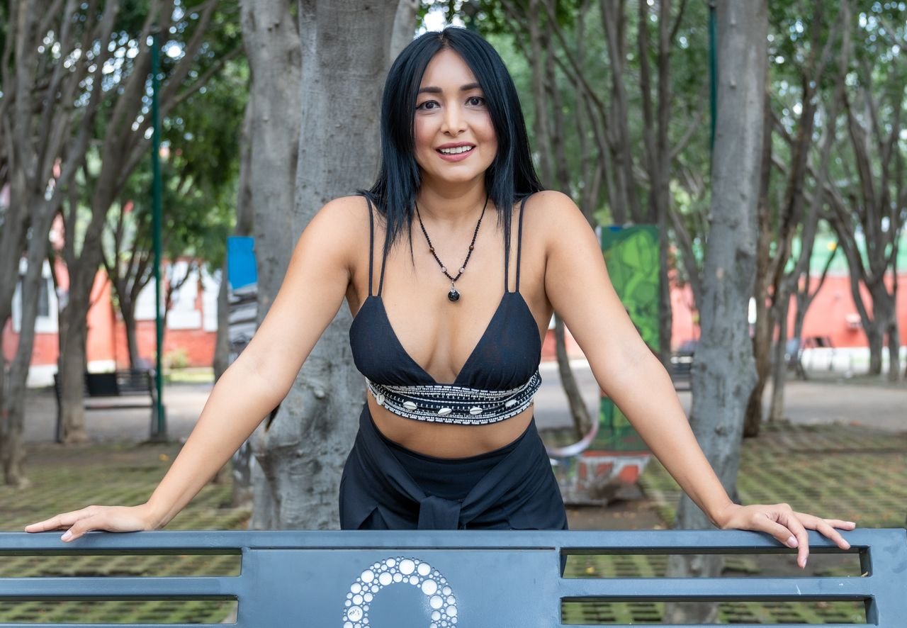 Smiling woman in a park bench at Ciudad de México, showcasing casual fashion.