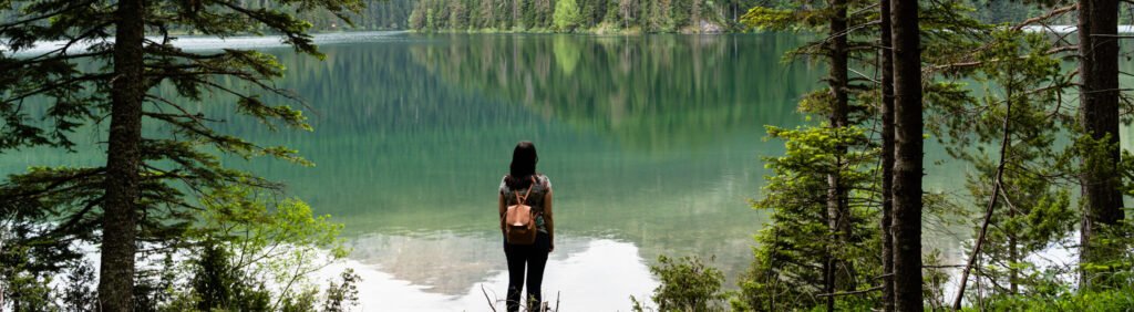 female with a backpack enjoying view of the black lake in durmitor national park, montenegro